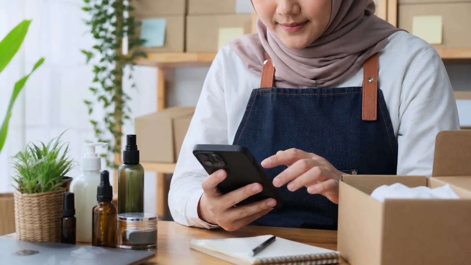 Pemilik usaha menyiapkan informasi produk lewat smartphone di samping produknya